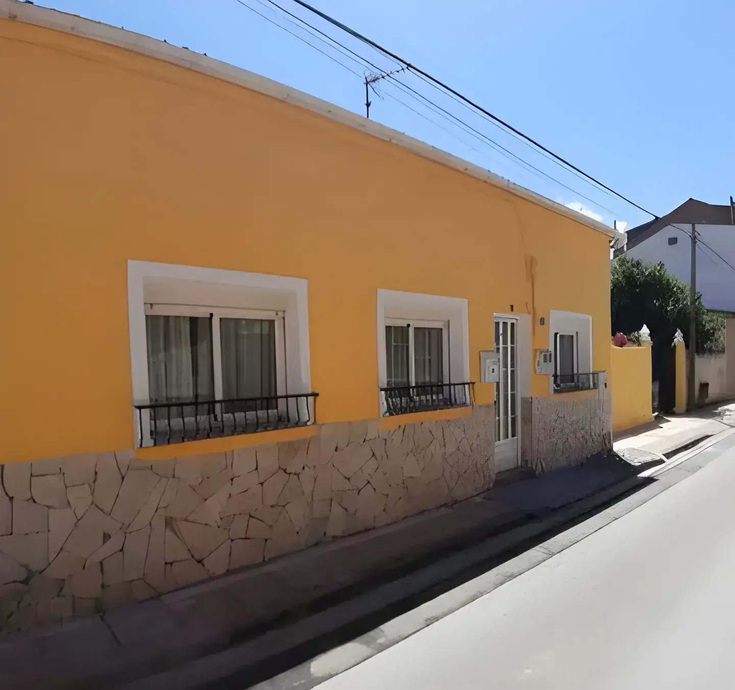 Los Pintores Ciudad Real Fachada de casa tradicional pintada en color amarillo con zócalo de piedra